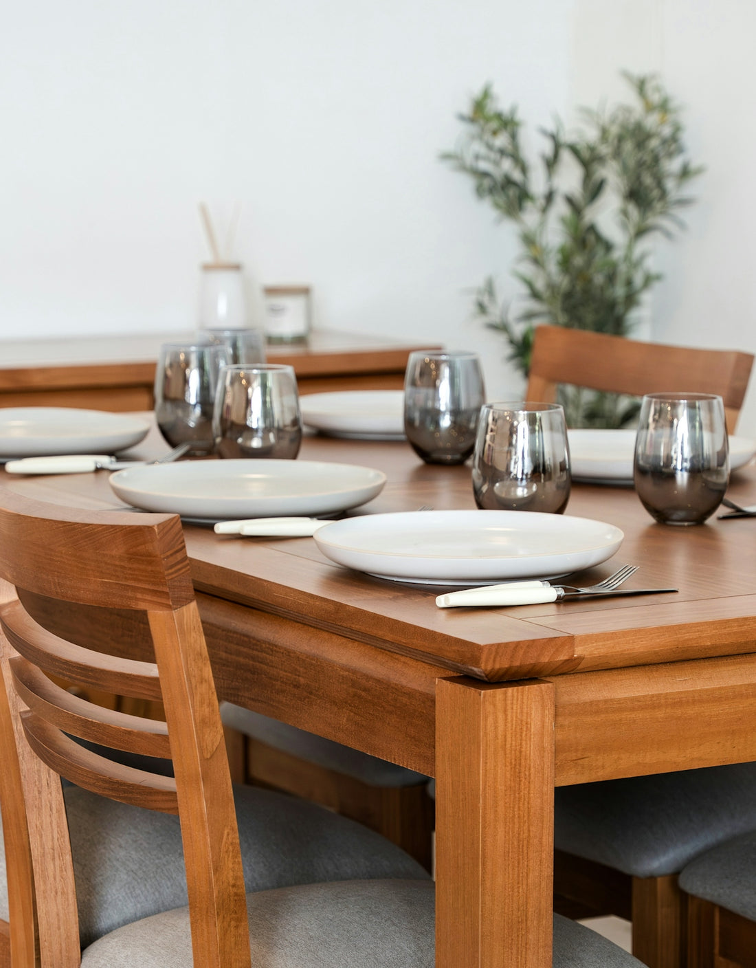 A wooden dining table set with plates and glasses.